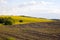 Sunny Landscape with Brown Plowed Field and Yellow Rapeseed Field.