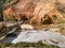 Sunny landscape with sandstone cliff on river bank, fast flowing river water