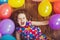 Sunny little girl in birthday party lying on wooden floor