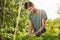 Sunny morning in garden. Close up of young good-looking mature hispanic male gardener in blue shirt smiling, working in