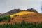 Sunny motley autumn landscape with sunlit gold mountain with green fir trees on mountainside under cloudy sky. Awesome alpine