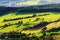 Sunny mountain valley with green fields and meadows. Scenic farmland landscape aerial view.