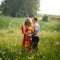 Sunny outdoor portrait of the happy smiling couple hugging on the blooming meadow. The wind is moving the blonde curly