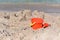 A sunny photo with a children`s beach pail and a spatula against a background of a sea