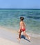 A sunny photo of a little girl in bikini running along a sea shore