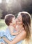 sunny portrait of kissing mother with small daughter in blue dresses