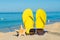 Sunny positive beach vacation. Yellow sandals, sunglasses and starfish on a background of the sea