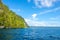 Sunny Rocky Shores with Rainforest and Yacht in the Distance