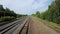 Sunny scenery of empty long railways laying along green line of bushes and trees