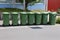 Sunny scenery of green garbage cans in the street