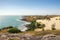 Sunny seascape. Coast of the desert with white sand and rocks in the water