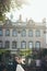 Sunny sensitive portrait of the adorable smiling newlyweds softly hugging at the background of the old house covered