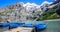 Sunny Summer Activities and recreation, rowing blue boats while enjoying beautiful Swiss alps view on Lake Oeschinen Oeschinensee