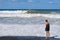 On a Sunny summer day, a teenager stands on the beach and watches the waves