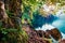 Sunny summer view of Fusine lake. First rays of the sun sparkle through the green leaves of the old forest. Bright morning scene