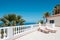 Sunny terrace with sun beds of ocean view house with palm trees anb blue sky copy space