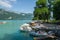 A sunny view on Lake Annecy, France, with boats on the quay and tourists in the park