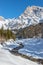 Sunny winter landscape in the alps: Mountain range, river, snowy trees, sunshine and blue sky