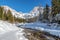 Sunny winter landscape in the alps: Mountain range, river, snowy trees, sunshine and blue sky