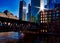 Sunrays extend over Chicago downtown during morning commute on a late February winter evening. El train passes over Chicago River.