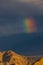 Sunrays falling on barren mountains with clouds and a rainbow