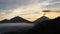 Sunrise above Lake Batur Covered with Clouds and Mount Agung Erupting Smoke - Seen from Top of Mount Batur in Bali, Indonesia.