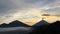 Sunrise above Lake Batur Covered with Clouds and Mount Agung Erupting Smoke - Seen from Top of Mount Batur in Bali, Indonesia.