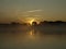 Sunrise above a river on foggy summer morning, the sky reflections in the water,  misty reflection in steaming water,