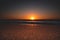 a sunrise on the beach, reflecting in the sand with some waves