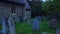 Sunrise drone footage reversing over sunken headstones in an overgrown cemetery