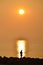 Sunrise with a fisherman and a small barge on horizon, Caorle, Italy