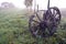 Sunrise on foggy autumn landscape with two antique wooden wheels
