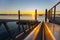 Sunrise glows on horizon and pier railings leading to harbor