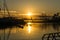 Sunrise in the harbor of Valencia, the sun rises between docked sailboats and cargo port cranes