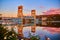 Sunrise with Houghton lift bridge and purple and pink clouds and flowering bushes and still water