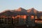 Sunrise illuminates the construction site, buildings, and the mountains of the Trans-Ili Alatau in warm colors.