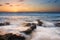 Sunrise landscape of ocean with waves clouds and rocks