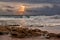 Sunrise landscape of ocean with waves clouds and rocks