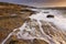 Sunrise landscape of ocean with waves clouds and rocks