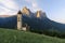 Sunrise landscapes of Church St. Valentin on grassy hilltop with view of rugged peaks of Mountain Schlern with alpenglow in backgr