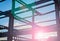 Sunrise lens flare through construction steel framework in silhouette against blue sky