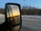 Sunrise in the morning reflect inside car side mirror during road trip in winter season.