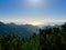 sunrise in the mountains covered tropical forest, with clouds over the ocean.