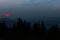 Sunrise in the mountains. Outlines of spruce tops and the sun`s rays make their way through clouds peaks. background