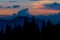 Sunrise in the mountains. Outlines of spruce tops and the sun`s rays make their way through clouds peaks. background. Coniferou