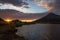 Sunrise next to volcano Mount Taranaki and lake in the forground