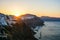 Sunrise in Oia, Santorini, Greece. Sun is rising behind the mountains above the traditional village of Oia in the Greek island of