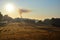 Sunrise, old countryside house with smoke from chimney, landscape with rural field.