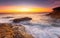 Sunrise over the ccean with some foreground rocks of eroded sandstone