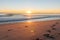 Sunrise over footprints on beach